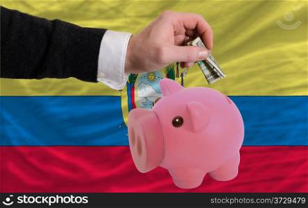 Man putting dollar into piggy rich bank national flag of ecuador in foreign currency because of inflation