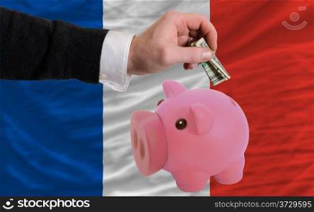 Man putting dollar into piggy rich bank national flag of france in foreign currency because of inflation