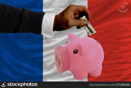 Man putting dollar into piggy rich bank national flag of france in foreign currency because of inflation