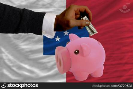 Man putting dollar into piggy rich bank national flag of franceville in foreign currency because of inflation