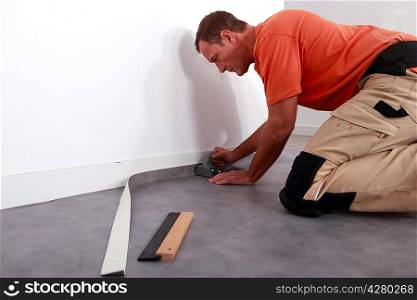 Man putting down linoleum on a baseboard