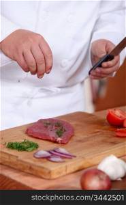 Man putting herbs on a piece of meat
