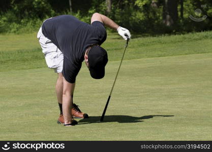 Man putting his hand in a hole on a golf course