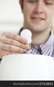 Man Putting Low Energy LED Lightbulb Into Lamp At Home