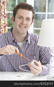 Man Putting Low Energy Lightbulb Into Lamp At Home