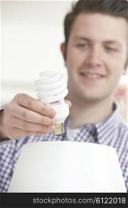 Man Putting Low Energy Lightbulb Into Lamp At Home