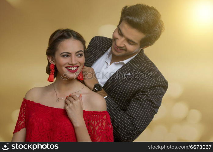 Man putting necklace on his girlfriend