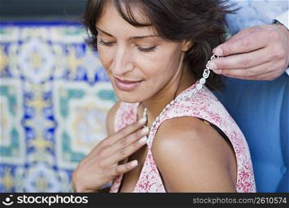 Man putting necklace on woman
