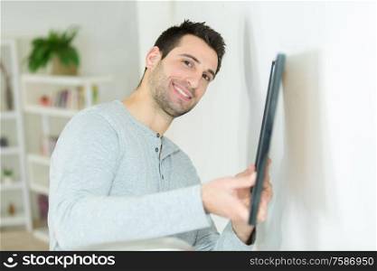 man putting picture frame onto wall