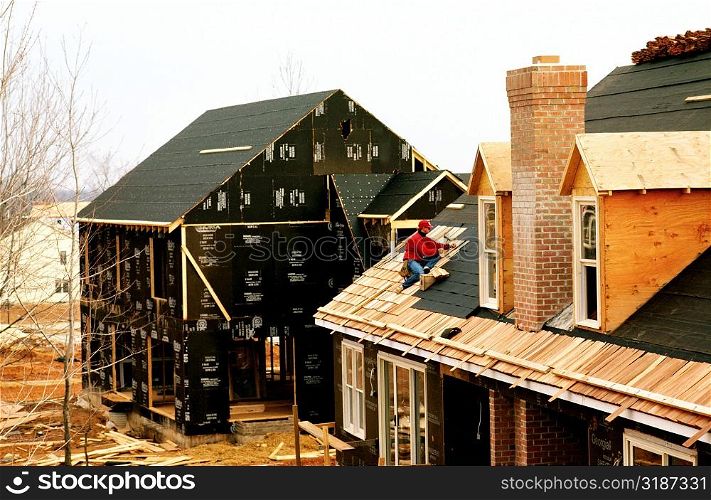 Man putting roof on new home