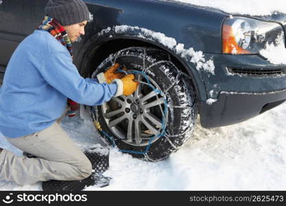 Man Putting Snow Chains Onto Tyre Of Car