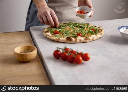 man putting tomatoes baked pizza dough with smoked salmon slices