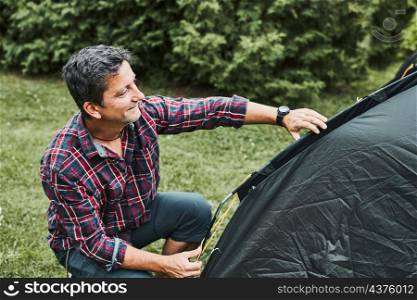 Man putting up a tent at camping during summer vacation. Preparing campsite to rest and relax. Spending vacations outdoors close to nature