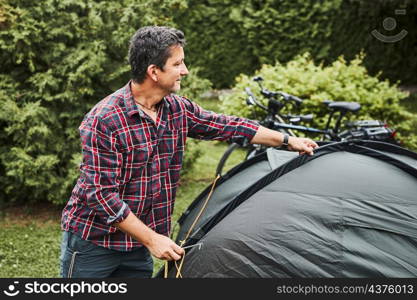 Man putting up a tent at camping during summer vacation. Preparing campsite to rest and relax. Spending vacations outdoors close to nature