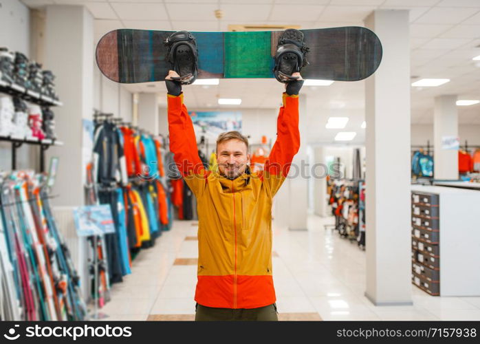 Man raised up the board for snowboarding, shopping in sports shop. Winter season extreme lifestyle, active leisure store, customer buying skiing equipment
