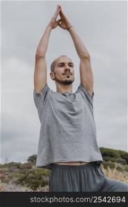 man raising his arms up while doing yoga outdoors