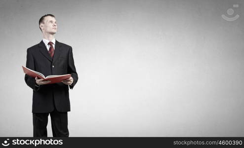 Man read book. Young businessman with red book in hands