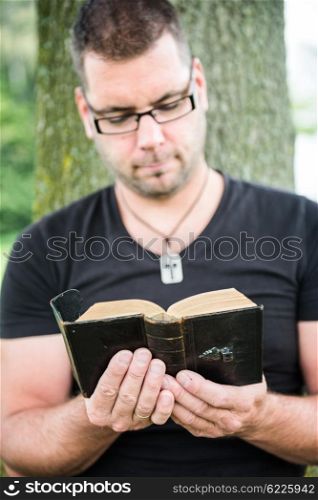 Man reading a bible outside