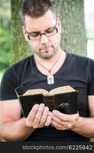 Man reading a bible outside