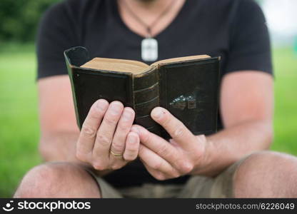 Man reading a bible outside