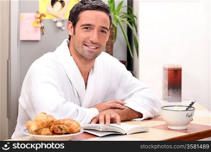Man reading a book and eating a continental breakfast