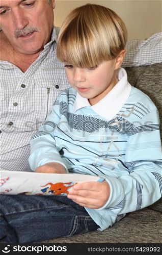 Man reading a book to a little boy