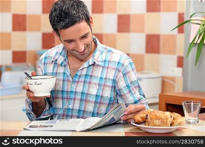Man reading a magazine at the breakfast table