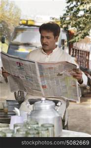 Man reading a newspaper at tea stall