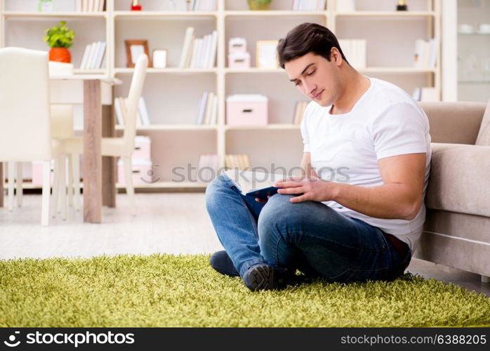 Man reading book at home on floor