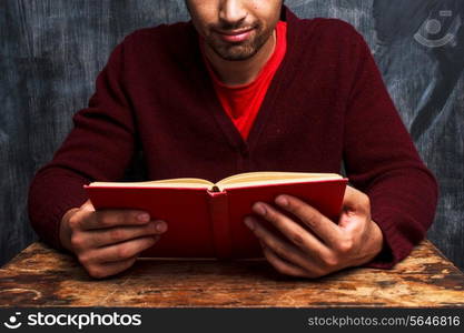 Man reading book by blackboard