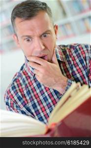 Man reading book, shocked expression