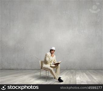 Man reading book. Young businessman sitting in chair with book in hands