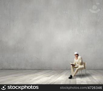 Man reading book. Young businessman sitting in chair with book in hands