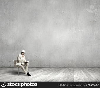 Man reading book. Young businessman sitting in chair with book in hands