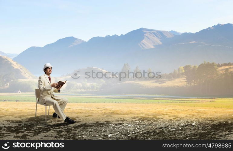 Man reading book. Young businessman sitting in chair with book in hands