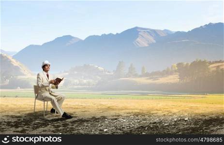 Man reading book. Young businessman sitting in chair with book in hands