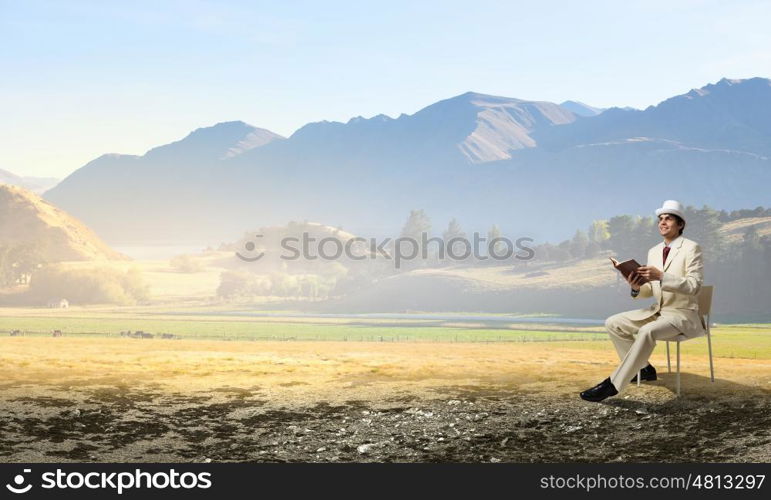 Man reading book. Young businessman sitting in chair with book in hands