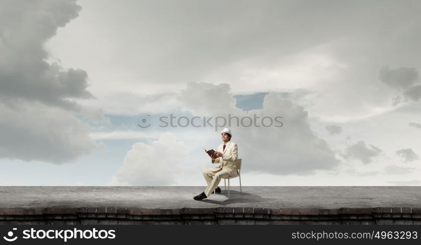 Man reading book. Young businessman sitting in chair with book in hands