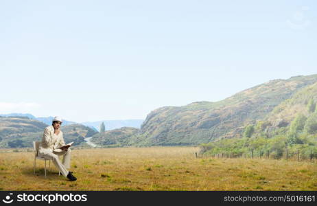 Man reading book. Young businessman sitting in chair with book in hands