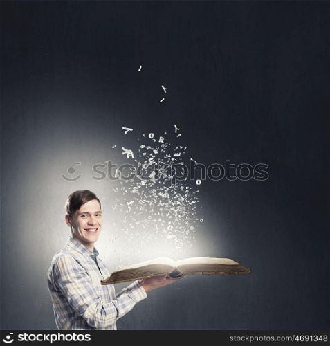 Man reading book. Young student guy with opened book in hands