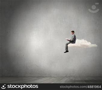 Man reading in isolation. Young businessman sitting on cloud and reading book
