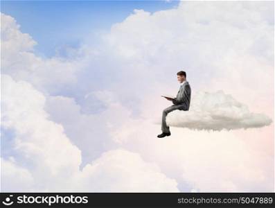 Man reading in isolation. Young businessman sitting on cloud and reading book