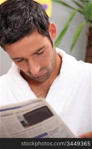 Man reading morning newspaper in kitchen