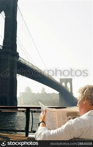 Man Reading Newspaper by Brooklyn Bridge