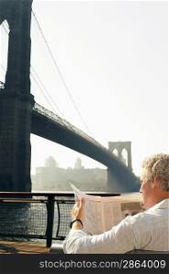 Man Reading Newspaper by Brooklyn Bridge