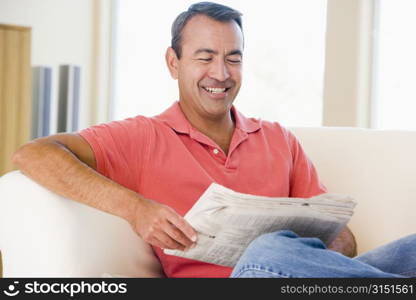 Man reading newspaper in living room smiling