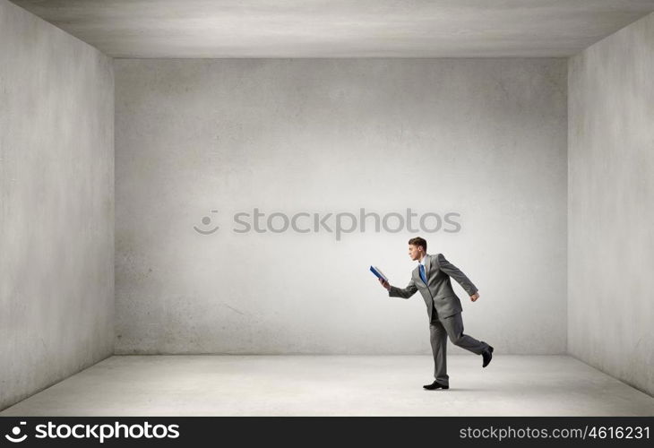 Man reading on the run. Young businessman running with opened book in hand