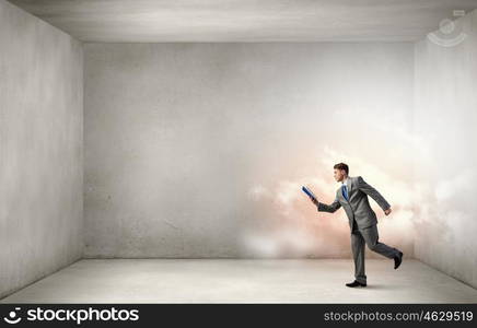 Man reading on the run. Young businessman running with opened book in hand