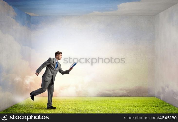 Man reading on the run. Young businessman running with opened book in hand