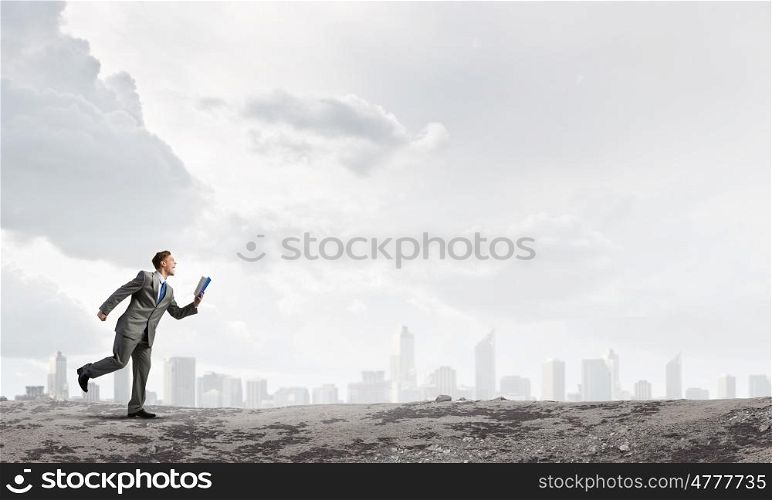 Man reading on the run. Young businessman running with opened book in hand
